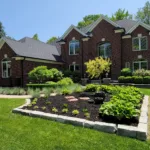 A professionally designed landscape with a variety of plants, trees, and mulch in a backyard in Rochester Hills, Michigan.