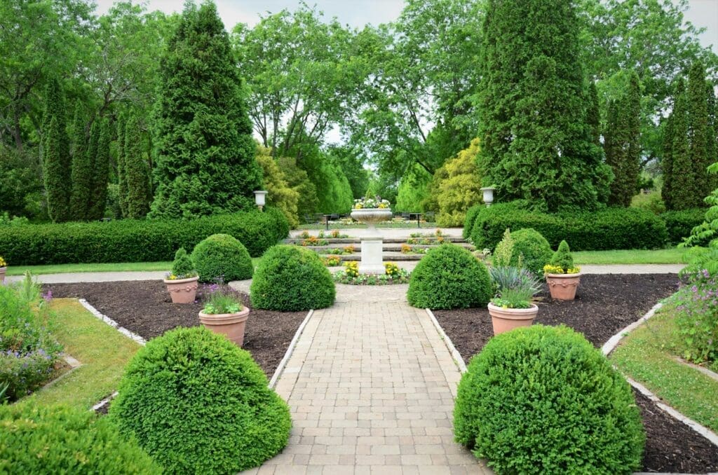 A modern, professionally designed landscape with a variety of plants, trees, and mulch in a backyard in Rochester Hills, Michigan.