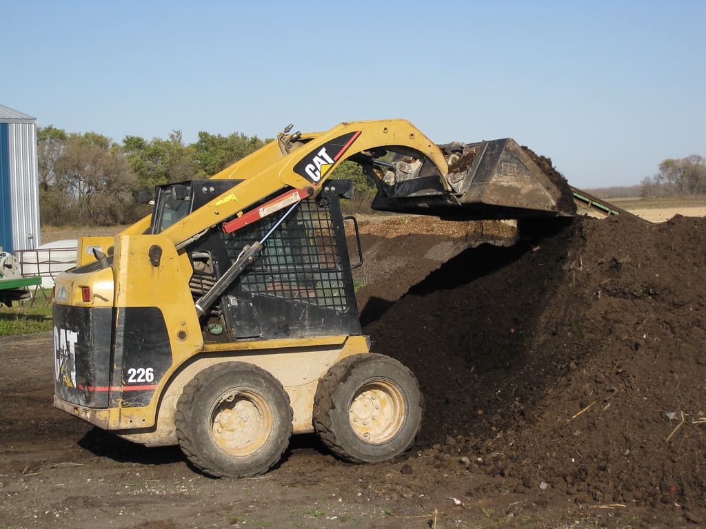 A close-up shot of a professional team grading a backyard to prepare for a new landscape